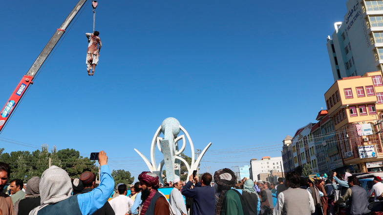 Eine Leiche hängt an einem Kran auf dem Hauptplatz der Stadt Herat im Westen Afghanistans und wird von Zuschauern gefilmt. Die Taliban haben die Leichen von vier Männern öffentlich aufgehängt, die einen Händler und seinen Sohn entführt haben sollen.