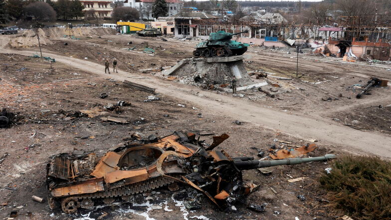 Anwohner gehen an einem beschädigten russischen Panzer in der Stadt Trostyanets, östlich der ukrainischen Hauptstadt Kiew, vorbei.