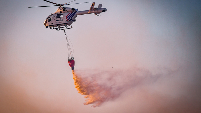 Mit Hilfe eines Hubschraubers wird aus der Luft versucht das Feuer im belgischen Naturschutzgebiet "De Liereman" zu löschen.
