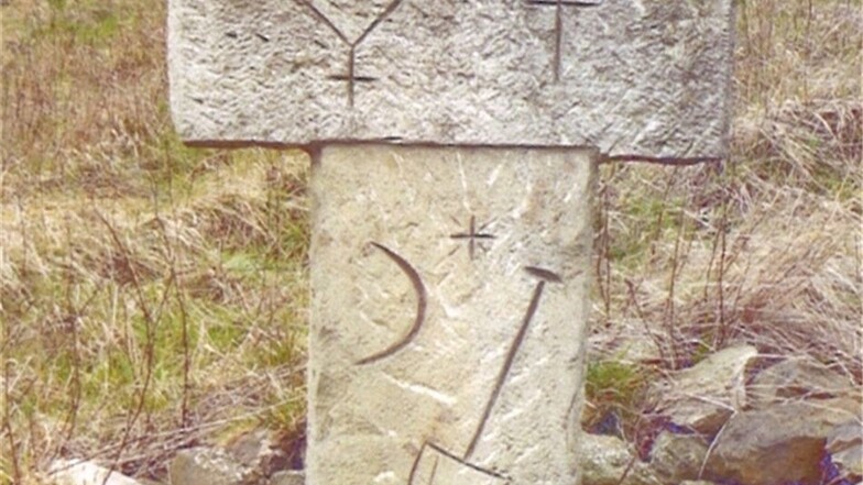 Mit einfachen Symbolen, Buchstaben und Zahlen erinnert das Steinkreuz bei Herbergen an die Sage vom unheilbar kranken Mädchen.