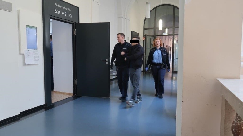 Einer der vier Kuriere aus Lübeck wird von Wachtmeistern in den Gerichtssaal gebracht. Nach einem halben Jahr in Untersuchungshaft kamen die Angeklagten nun auf freien Fuß.