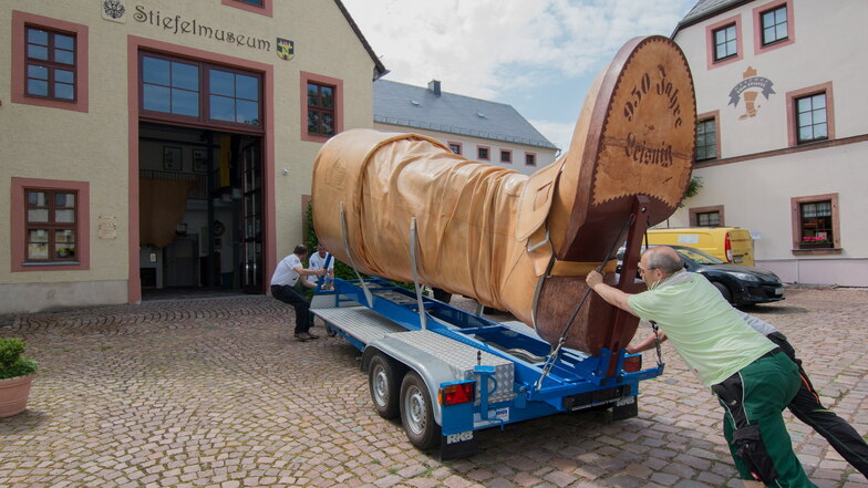 Mit vereinten Kräften wird der Leisniger Riesenstiefel nach seiner Sanierung zurück ins Museum geschoben.