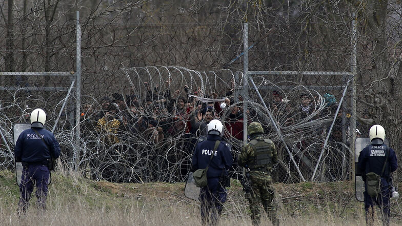 Bereitschaftspolizisten aus Griechenland schützen die griechisch-türkischen Grenze bei Kastanies, während Migranten hinter einem Zaun versuchen, aus der Türkei nach Griechenland zu kommen.