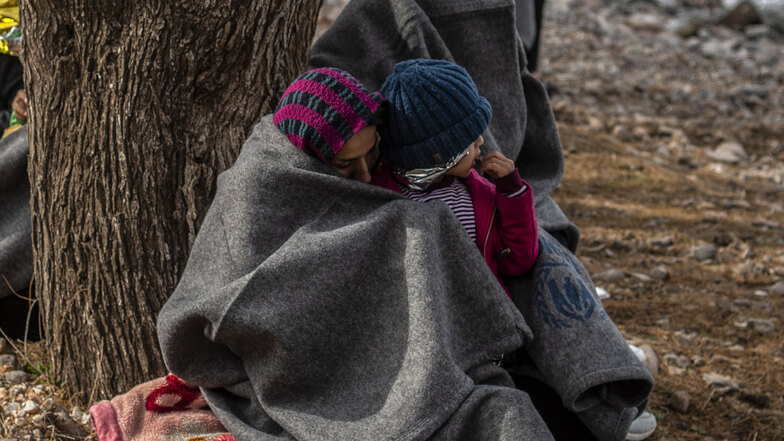 Migranten aus Afghanistan sitzen nach ihrer Ankunft auf der griechischen Insel Lesbos am Strand.