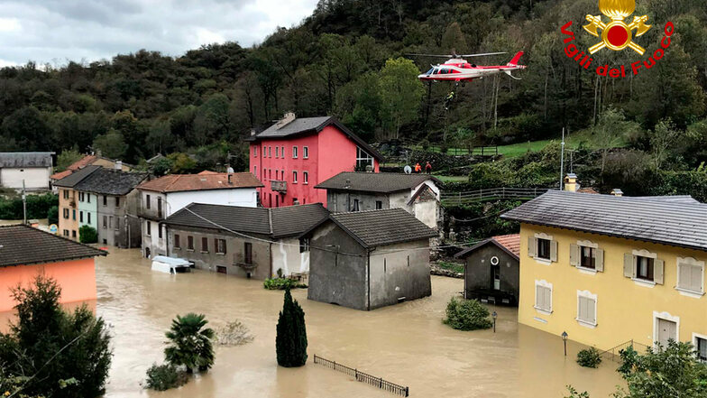 Ein Feuerwehrhubschrauber überfliegt eine überschwemmte Stadt in der norditalienischen Region Piemont.