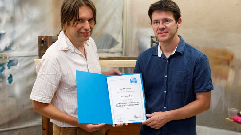 Der Gesundheitsmanager der IKK classic, Swen Fromelius (rechts), überreicht Tischlermeister "Frank Pohl die Urkunde mit dem Siegel für "Exzellentes betriebliches Gesundheitsmanagement.