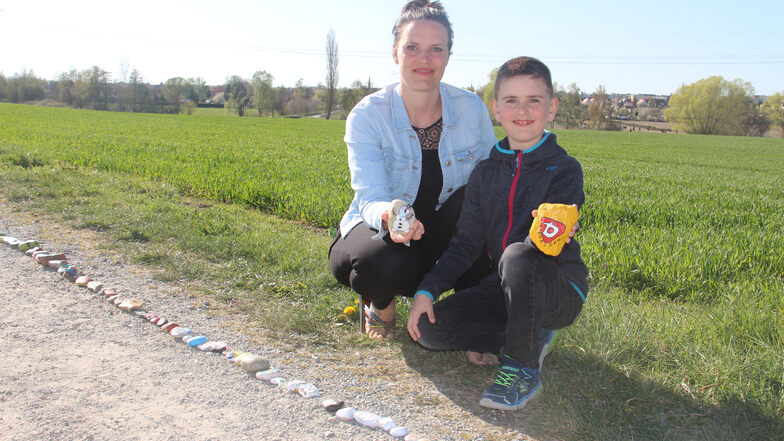 Sandra Mittasch und ihr Sohn Louis freuen sich, dass, die Schlange aus bemalten Steinen in Auritz immer weiter wächst.