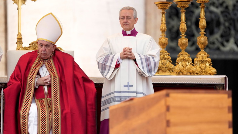 Papst Franziskus (l.) sitzt während der öffentlichen Trauermesse hinter dem Sarg von Benedikt XVI.