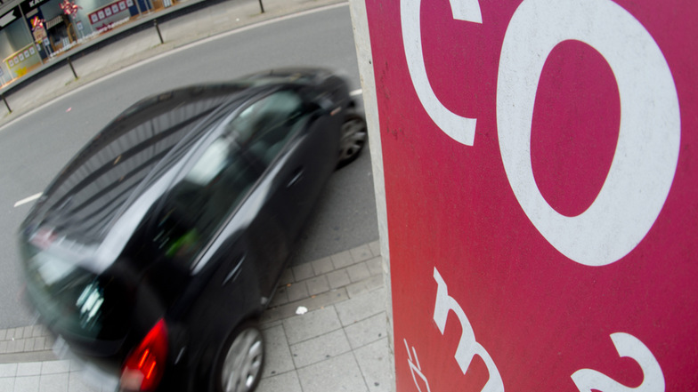 Ein Auto fährt an einem Schild mit Aufschrift "CO2" (Kohlendioxid) vorbei.