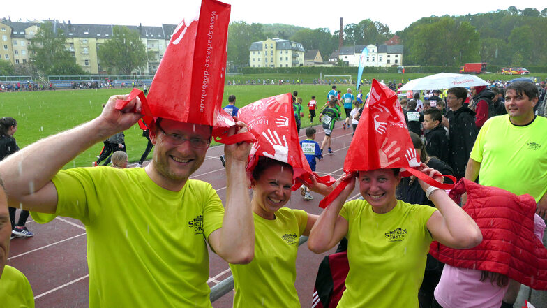 Matthias, Linda und Christiane (von links) funktionierten die Verpflegungstüten kurzerhand zu Regenmützen um.