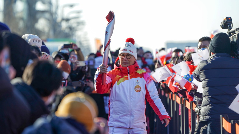 Der erste Fackelträger Luo Zhihan, ehemaliger Eisschnelllauf-Weltmeister, trägt die Fackel während des olympischen Fackellaufs.