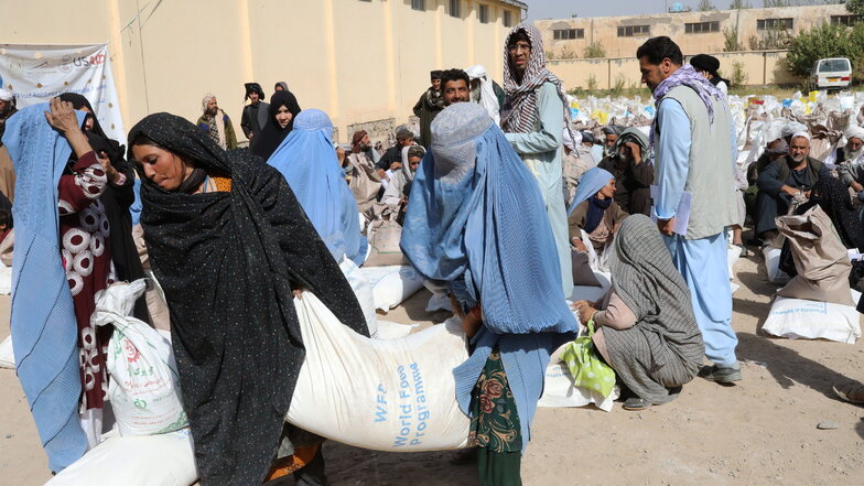 Afghanistan, Herat: Frauen verlassen eine Verteilungsstelle des Welternährungsprogramm WFP am Stadtrand mit Lebensmittelrationen. Die Rationen bestehen aus Weizenmehl, Erbsen, Öl und Salz für jede Familie.