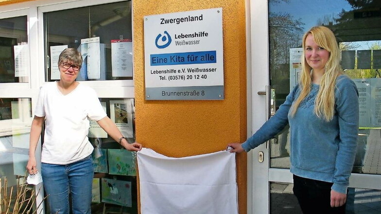 Die Kita Zwergenland des Lebenshilfe-Vereins Weißwasser ist nun eine Kita für alle. Leiterin Kathrin Thöns und Susanne Kotte vom Elternrat enthüllten jetzt die Tafel.