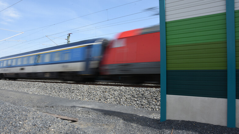 Ein Zug verschwindet in Großenhain hinter einer Lärmschutzwand. Die Bahn will weitere Schutzwände und Schienenstegdämpfer einbauen, um Lärm zu reduzieren.