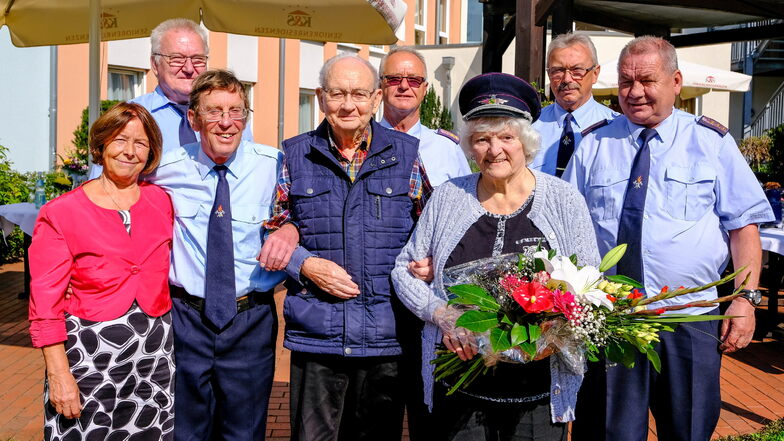 Gratulation von den Kameraden der Radebeuler Feuerwehr für Ingeburg Jander, mit Blumen und Feuerwehrmütze.