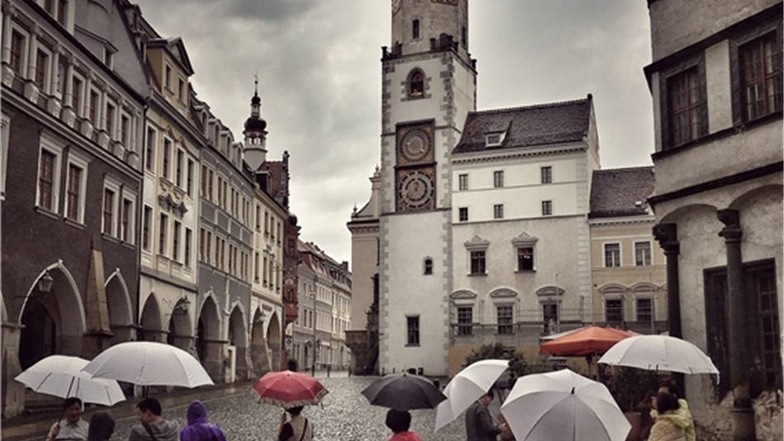 Asiatische Touristen betrachten das Görlitzer Rathaus am Untermarkt. Vom schlechten Wetter lassen sich die Touristen nicht beeindrucken.