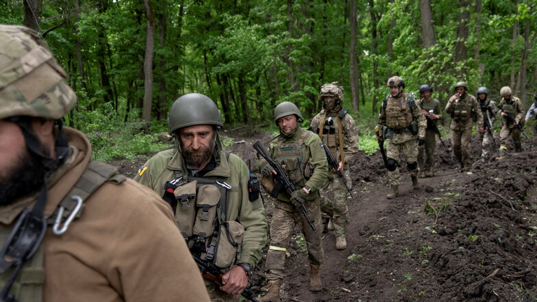 Ukrainische Soldaten gehen in der Nähe eines kürzlich zurückeroberten Dorfes nördlich von Charkiw in der Ostukraine durch den Wald.
