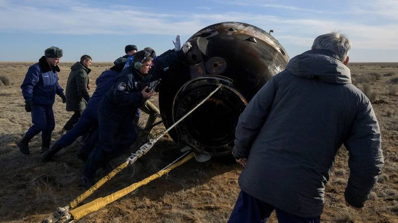 Mitglieder von russischen Such- und Rettungsteams erreichen die gelandete Sojus-Kapsel.