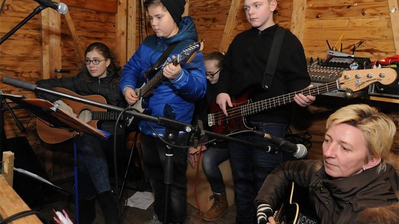 Schüler der Oberschule Hartha bieten den Zuhörern beim Adventssingen traditionelle Weisen, aber auch moderne, rockige Songs. Wegen Regens spielen sie auch in einer Holzbude. Dem Publikum gefällt es trotzdem.   Foto:  /  /
