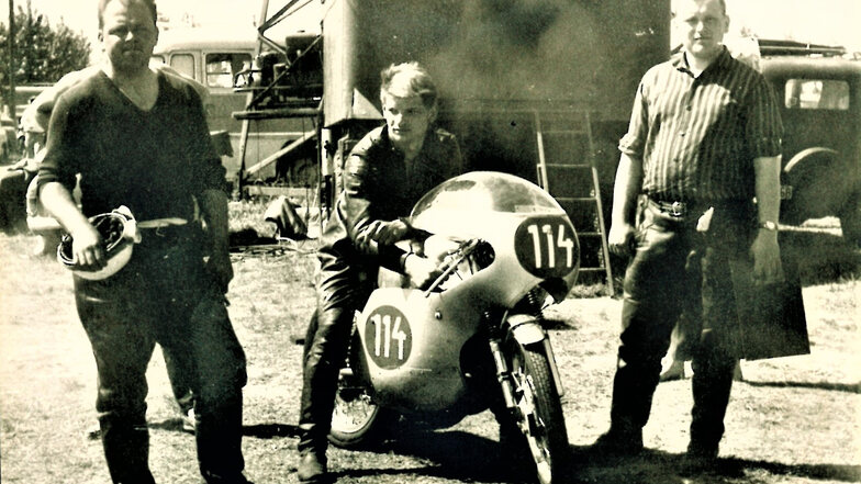 Wolfgang Gast auf dem Motorrad mit zwei seiner Helfer. 1964 belegte er beim Weltmeisterschaftslauf auf dem Sachsenring Platz sechs.