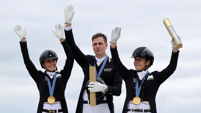 Jessica von Bredow-Werndl (l.), Frederic Wandres und Isabell Werth jubeln bei der Siegerehrung über Gold.