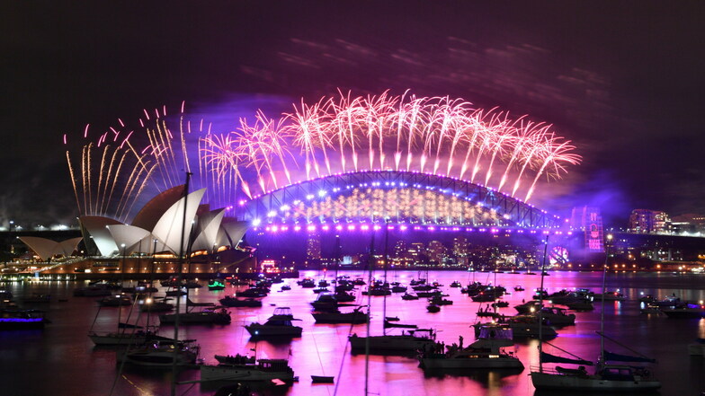Australien, Sydney: Im Hafen treibende Boote werden vom Feuerwerk beleuchtet, das von der Sydney Harbour Bridge und dem Opernhaus (l) aus gestartet wird.