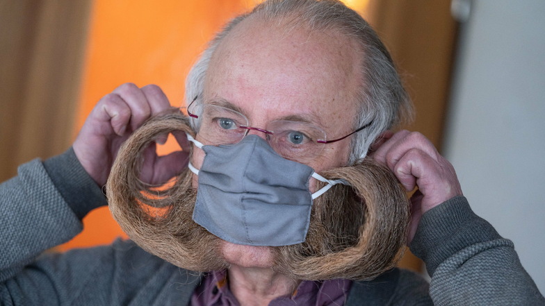 Jürgen Burkhardt, mehrfacher Bartweltmeister, demonstriert das Anlegen seines für ihn von einer Schneiderin angefertigten Mundschutzes. Mit einer FFP2-Maske wird das nicht so einfach möglich sein.