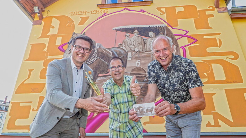 Oberbürgermeister Sven Liebhauser (CDU), Graffiti-Künstler Frank Schäfer und Vereinschef Jörg Lippert bei der Einweihung des Kunstwerkes am Giebel des Döbelner Pferdebahnmuseums.