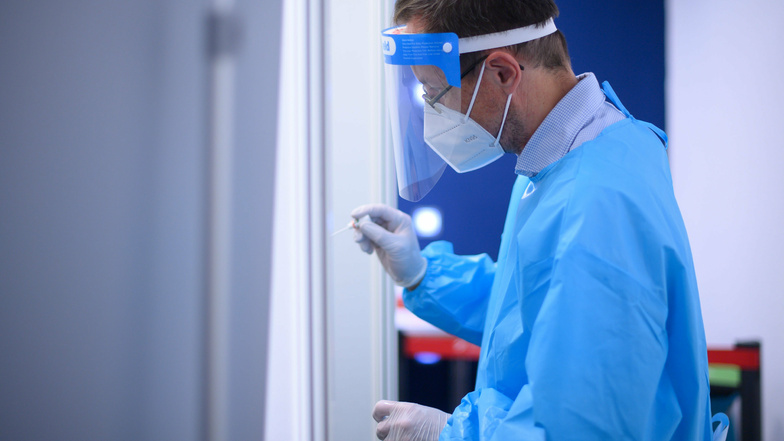 Ein Arzt der Kassenärztlichen Vereinigung Sachsen macht in der Corona-Teststation für Urlaubsrückkehrer am Flughafen Dresden einen Coronavirus-Test.