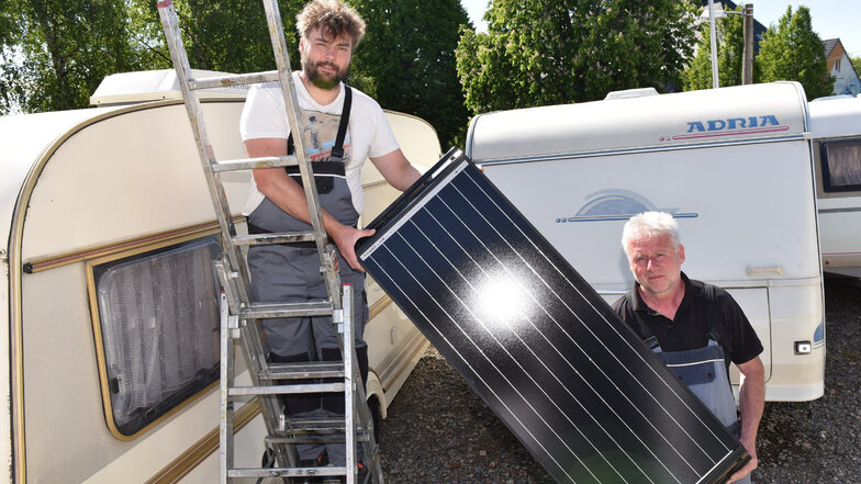 Uwe (re.) und Marcel Lehmann vom Karrosseriebau Lehmann in Paulsdorf montieren ein Solarpanel an einem Wohnwagen.