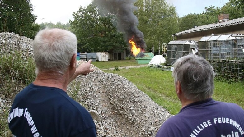 Günter Knobloch und Peter Winter haben das Feuer für die Übung vorbereitet und beobachten den Brand im Container, bis die alarmierten Kameraden eintreffen.