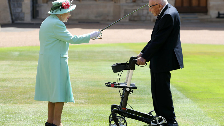 Königin Elizabeth II. (l) schlägt Tom Moore (r), Weltkriegsveteran und Rekord-Spendensammler, während einer Zeremonie im Freien auf Schloss Windsor zum Ritter.