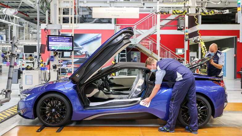Leipzig: Zwei Mitarbeiter gehen am Ende der Fertigungslinie noch einmal mit einem Tuch über den letzten BMW i8.