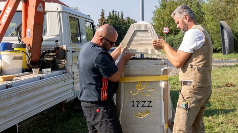 Henry Rothenbücher (li.) und Andreas Hain von der Hain Steinrestaurierung Meißen brachten am Mittwoch in Großenhain das Kopfteil an den Viertelmeilenstein an.