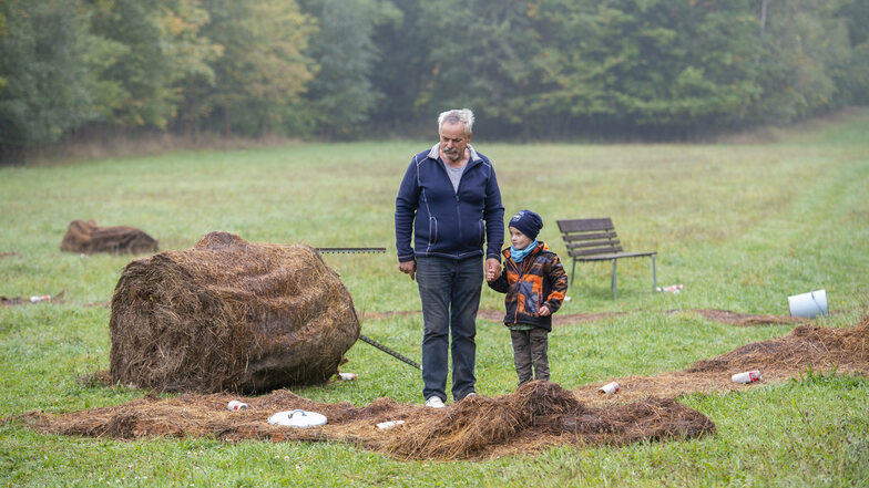 Bauer Christian Junghanns und sein Enkel Finn stehen auf der Wiese am Birkenhainer Weg, wo Jugendliche randaliert haben.