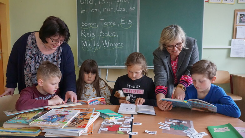 Maria Langenegger (li.) hilft den Bad Brambacher Grundschülern Helge, Alina, Juna und Phil beim Lesenlernen. Schulleiterin Annett Stahl ist froh, dass sie sie dafür gewinnen konnte.