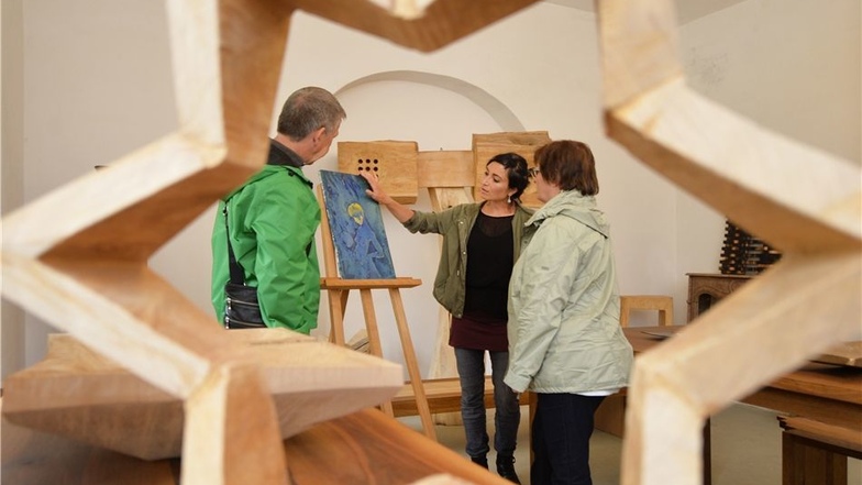 Die Künstlerin Nadja Blottner (M.) erläutert den Gästen Brigitte und Edgar Macke aus Schwerin zum Tag des offenen Ateliers in der Grauen Presse in Sörnewitz das Bild „Die kleine Erde“.