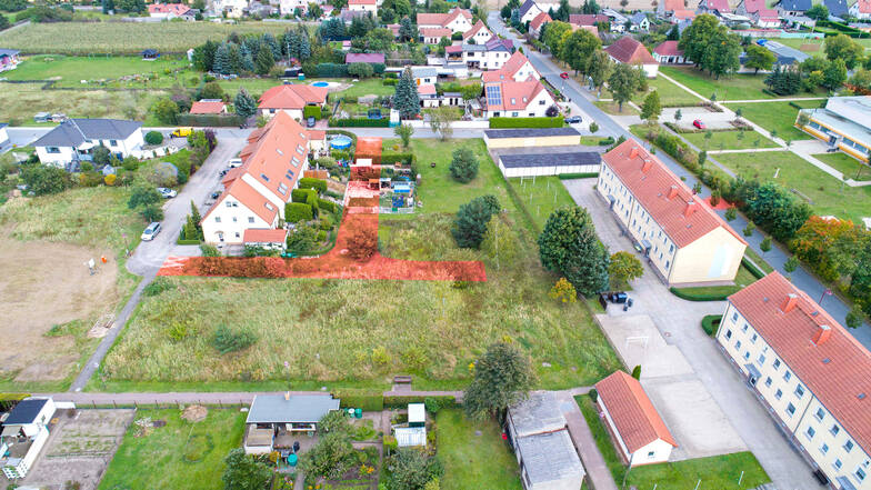 Diese Luftbild-Aufnahme stammt von 2017. Rotbraun eingezeichnet ist die Straße, die eigentlich geplant war. Doch ein paar Bewohner der Reihenhäuser (links) hatten schon damals ihre Grundstücke erweitert.
