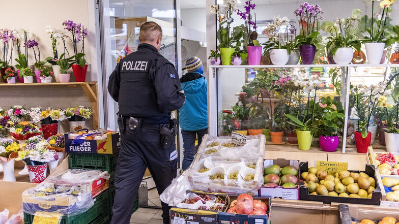 Ein Bundespolizist in einem der durchsuchten Objekte, im Hintergrund die 38-jährige mutmaßliche Hehlerin.