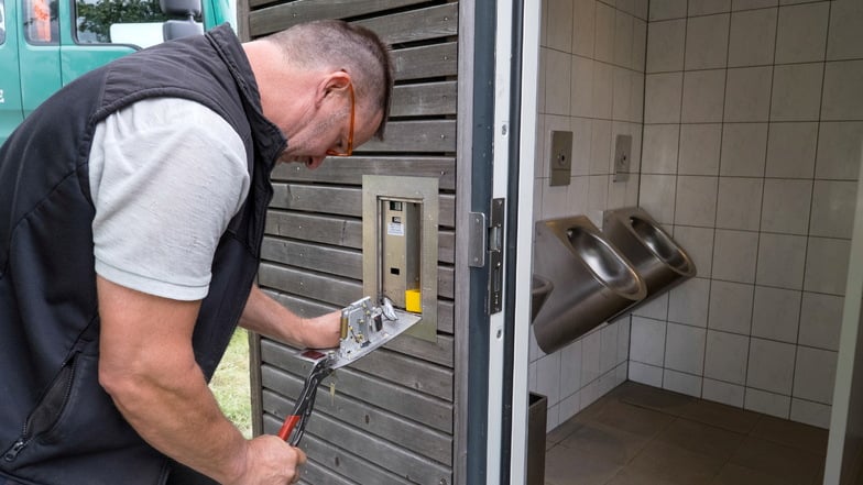 Ein Mitarbeiter der Firma Bullmann repariert den Münzautomaten der Toilette am Nordoststrand.