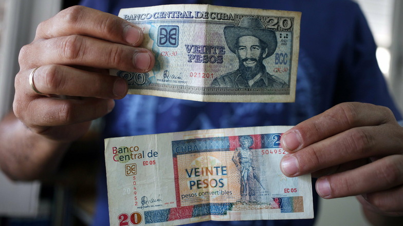 Ein Mann zeigt zwei Geldscheine zu je 20 Pesos, einen der offiziellen Landeswährung Peso CUP (oben) und einen von Peso Cubano Convertible CUC (unten). Kuba will zum Beginn des kommenden Jahres eine seiner zwei Währungen abschaffen.