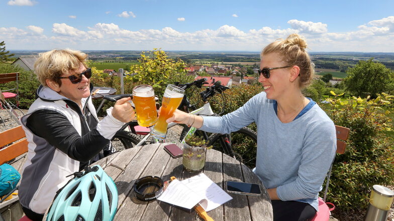 Prost – sich endlich wieder bewirten lassen! Mutter und Tochter machen während einer Radtour Halt in einem Biergarten in Uttenweiler-Offingen in Baden-Württemberg.