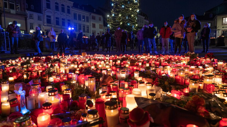Menschen gedenken am Abend in Trier vor der Porta Nigra für die Opfer einer Amokfahrt und stellen Kerzen ab.