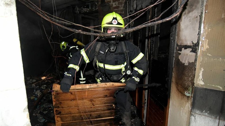 Feuerwehrleute tragen Reste einer Sauna aus dem Gebäude.