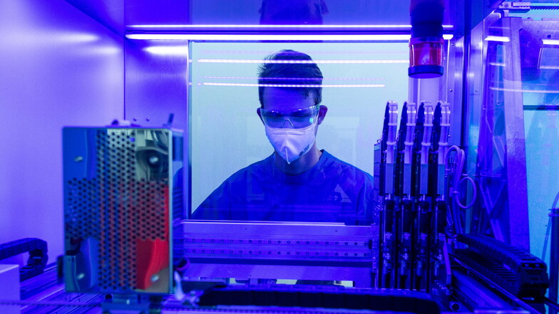Ein Laborant steht in einem Labor an einem PCR-Vollautomaten zur Untersuchung von Corona-Abstrichen.