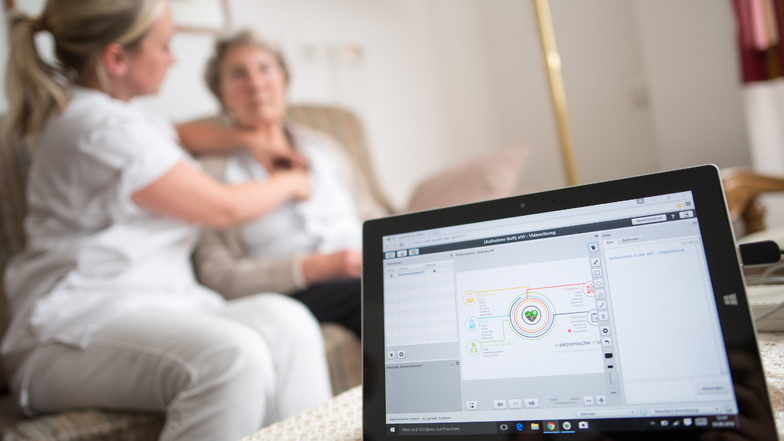 Eine Pflegerin legt einer Heimbewohnerin bei einer elektronischen Visite ein EKG-Gerät an. Das überträgt die Daten an einen Tablet-Computer und von dort aus zum Arzt.