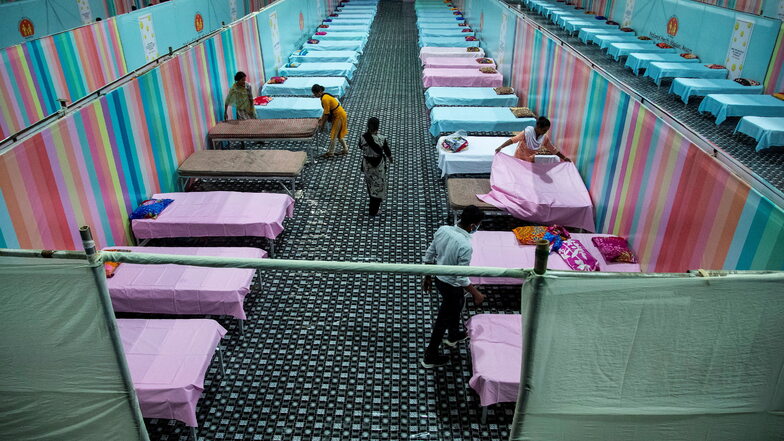 Indien, Gauhati: Arbeiter stellen provisorische Betten für Corona-Patienten in einer Stadionhalle auf.