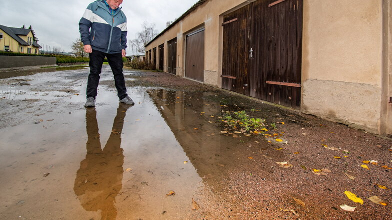 Rainer Künzel steht vor seiner Garage in Keuern in einer Seenlandschaft. Das Gelände hat keine Entwässerung, bei Regen bilden sich große Pfützen. Die Stadt will ab kommenden Jahr mehr Pacht für die Grundstücke.