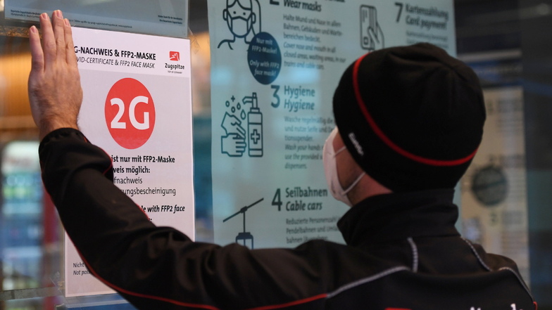 Bayern, Grainau: Ein Mitarbeiter der Zugspitzbahn klebt einen 2G Hinweis an die Eingangstür der Talstadtion. Auf eine bundesweite 2G-Regel wollen die Ampel-Partner wohl verzichten.