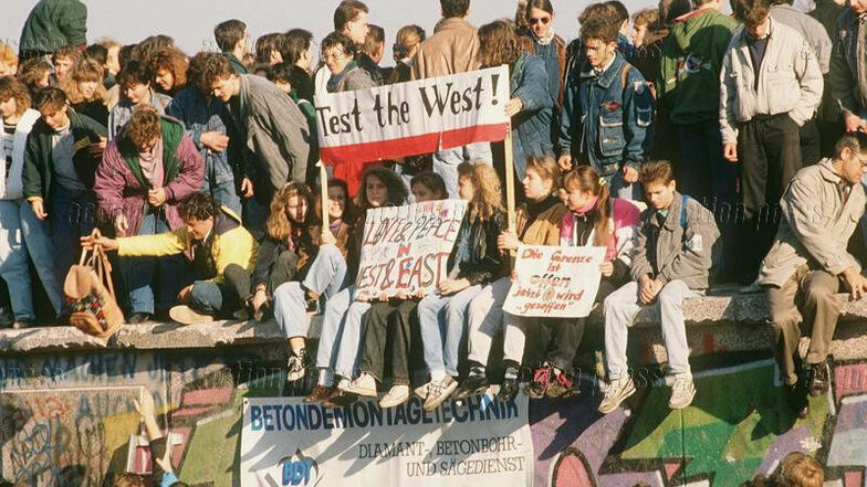 Menschen auf der Berliner Mauer in den Tagen des Mauerfalls 1989. Ob sie damals geahnt haben, wie lange die Wiedervereinigung von Ost und West dauern wird?